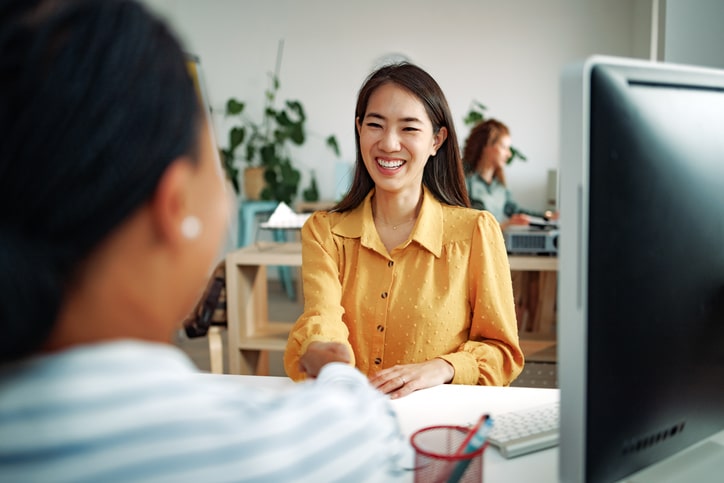 Two well dressed businesswomen shaking hands at the office